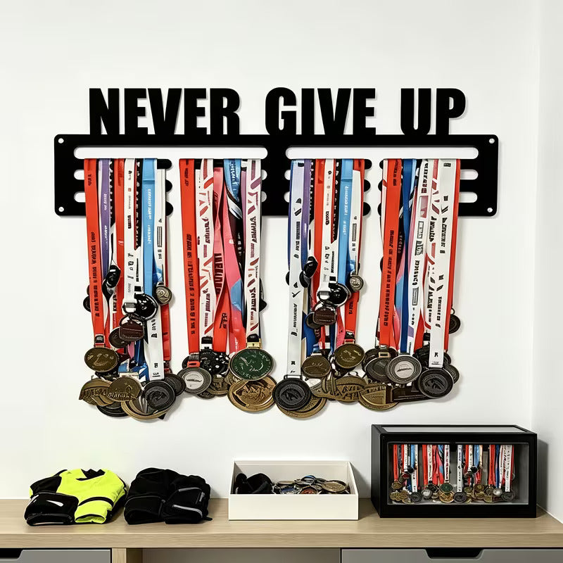 Never Give Up medal hanger on white wall above desk with medals and gloves