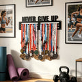Never Give Up medal hanger mounted on wall with running photos, yoga mats and kettlebell